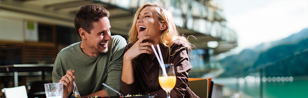 Una pareja riendo mientras come en un café al aire libre.