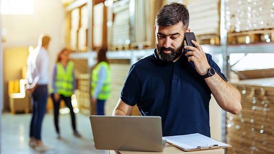 Hombre de negocios en un almacén trabajando en su computadora portátil.