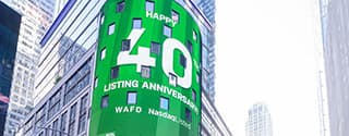 Green Nasdaq display on a city building celebrating WaFd's 40th listing anniversary.