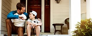 Father and his son laughing and talking on their porch at home.