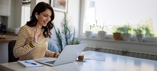 Smiling woman having a video call via laptop computer in the home office.