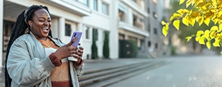 Woman laughing while looking at her mobile phone.