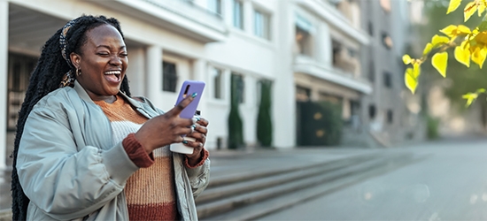 Woman laughing while looking at her mobile phone.