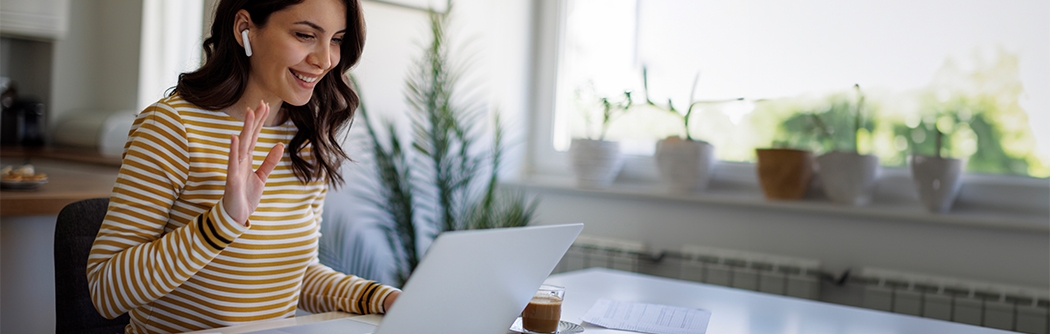 Smiling woman having a video call via laptop computer in the home office.