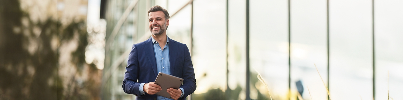 Happy businessman walking outside building.