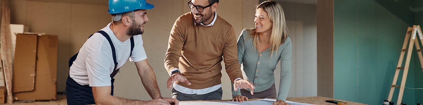 A couple with a contractor looking at their home remodeling plans.