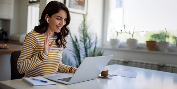 Smiling woman having a video call via laptop computer in the home office.