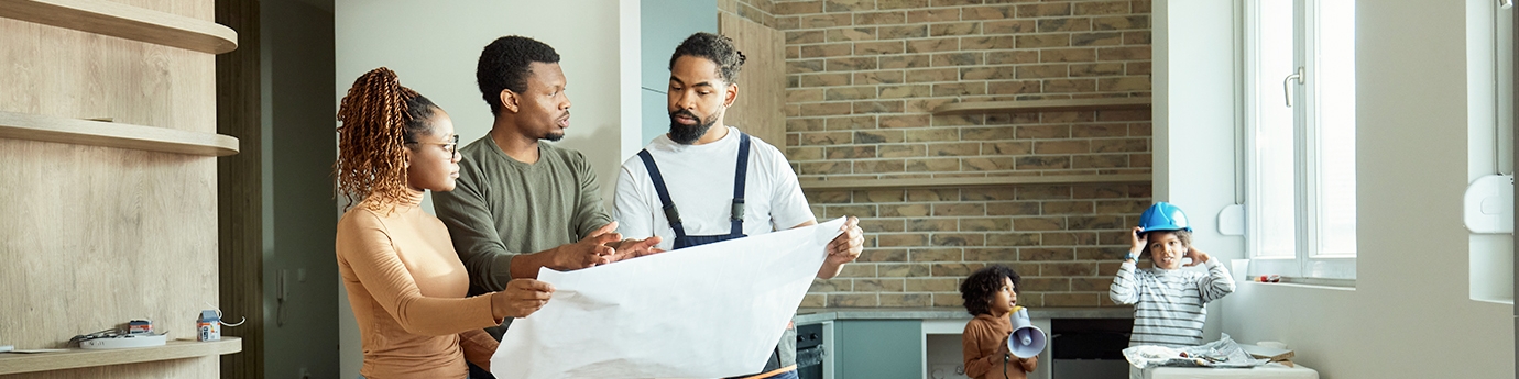 Couple looking at blueprints with contractor while kids play.