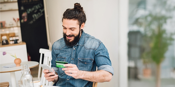 Man making a mobile credit card purchase in a cafe.