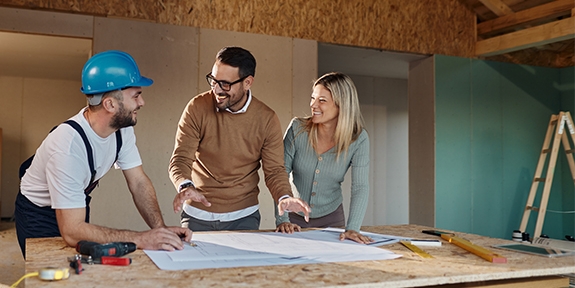 A couple with a contractor looking at their home remodeling plans.