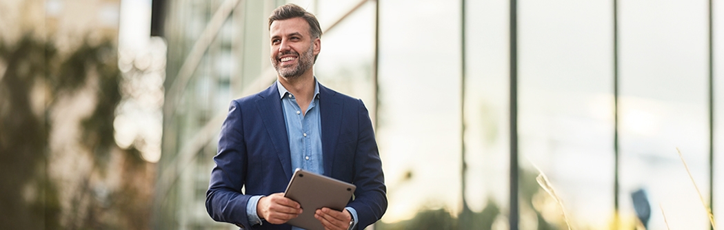 Happy businessman walking outside building.