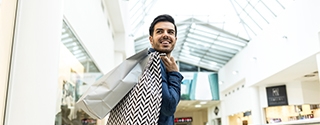 Man walking through a shopping mall with bags.