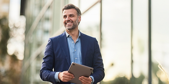 Happy businessman walking outside building.