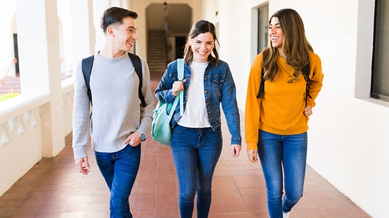 Three students walking down a school hallway.