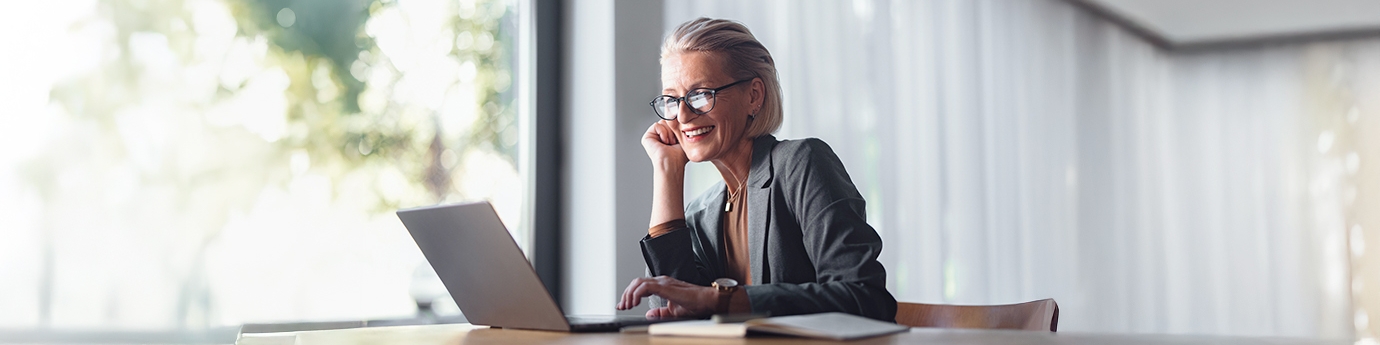 Business woman with laptop at desk in office.