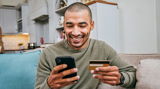 A young man using his smartphone to make online card payment.