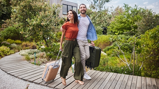 Happy Couple walking outdoors with luggage.