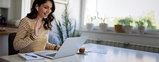 Smiling woman having a video call via laptop computer in the home office.