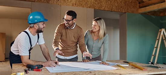 A couple with a contractor looking at their home remodeling plans.