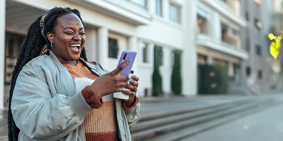 Woman laughing while looking at her mobile phone.