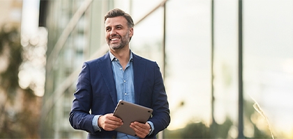 Happy businessman walking outside building.