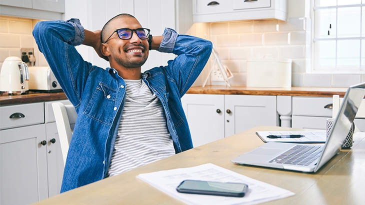 Young man relaxing while working on his laptop at home.