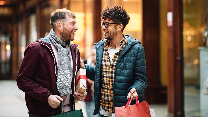 Two men talking and holding holiday gifts.