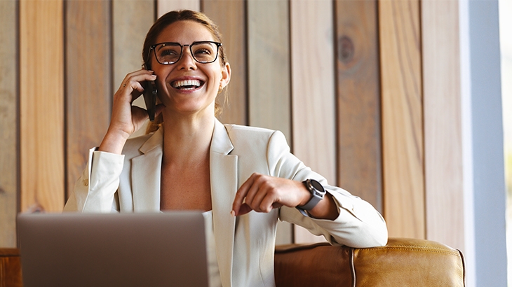 Businesswoman laughing on her phone with a laptop.