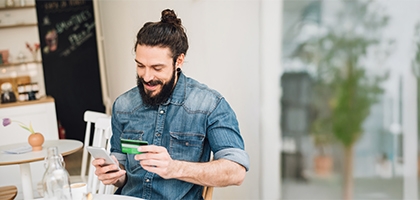 Man making a mobile credit card purchase in a cafe.