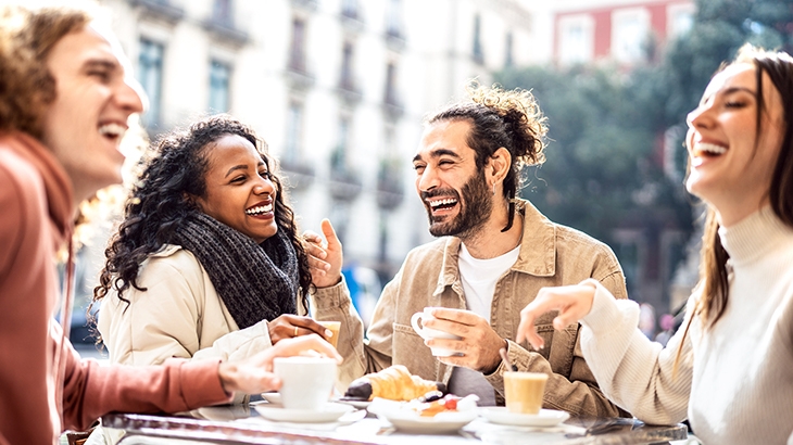 Friends laughing while eating breakfast at a restaurant.