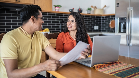 Couple in their kitchen reviewing accounting on a laptop.