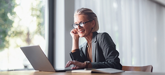 Business woman with laptop at desk in office.