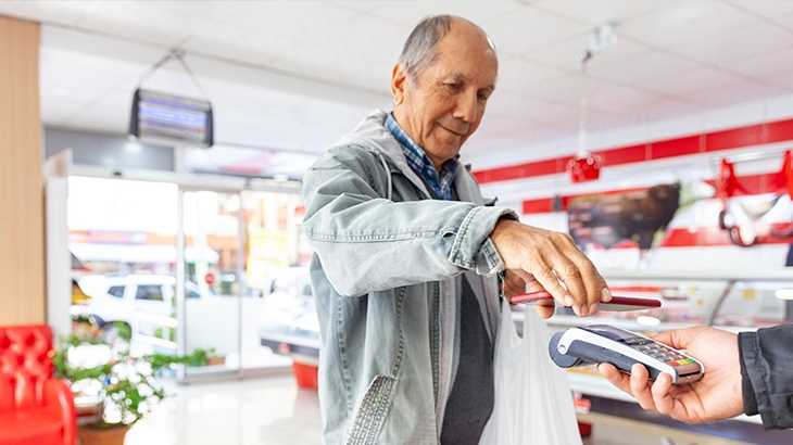 Senior man making a contactless mobile phone payment.