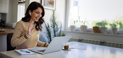 Smiling woman having a video call via laptop computer in the home office.