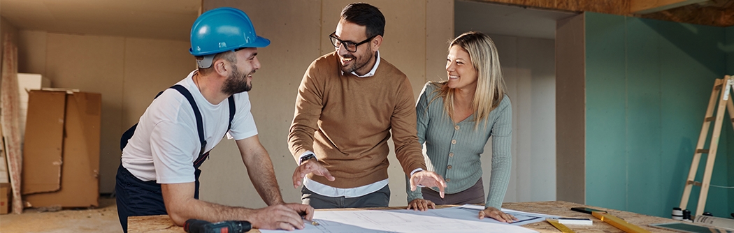 A couple with a contractor looking at their home remodeling plans.