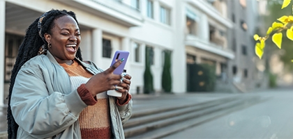 Woman laughing while looking at her mobile phone.