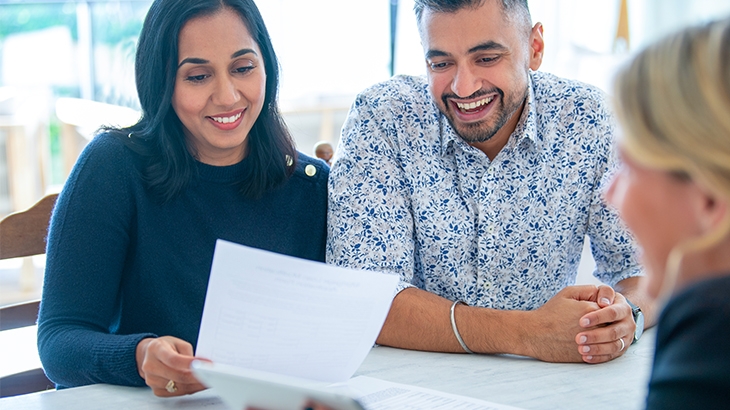 Loan officer explains loan details to couple in office.