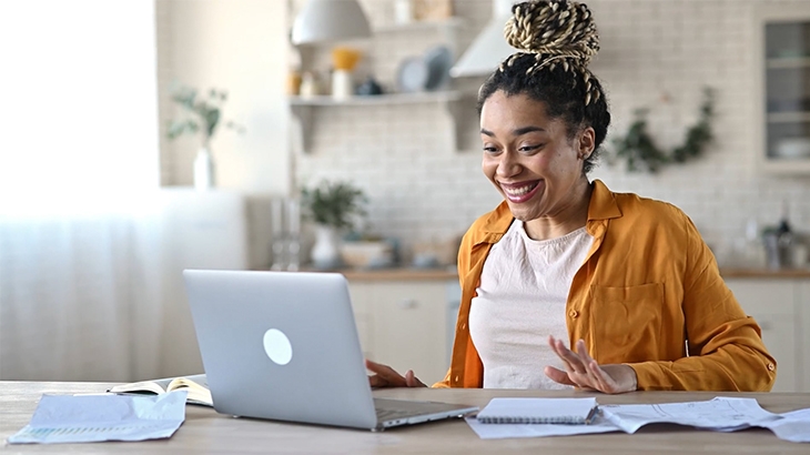 Excited woman working on her laptop in the kitchen.