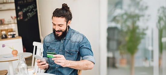 Man making a mobile credit card purchase in a cafe.