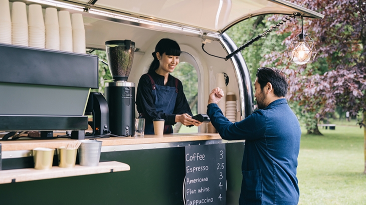 Customer at mobile coffee truck making contactless payment using a smartwatch.