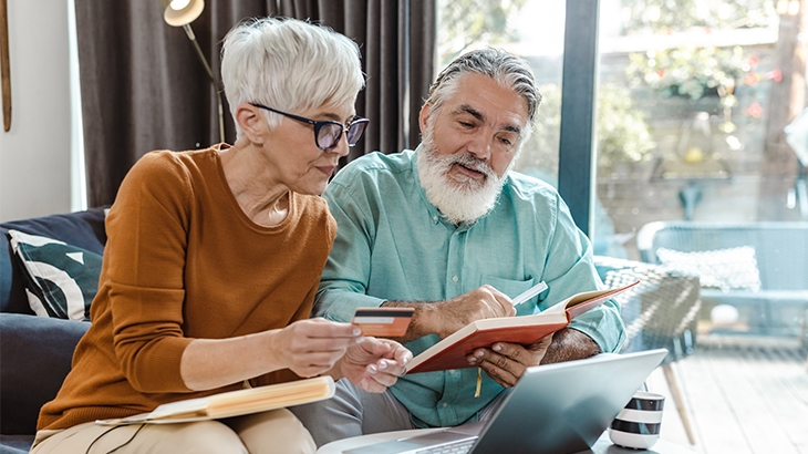 Senior couple sitting on the sofa and discussing finances.