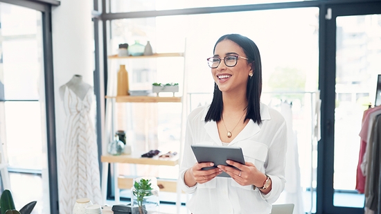 Happy Businesswoman holding tablet in clothing store.