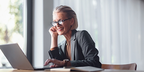 Business woman with laptop at desk in office.