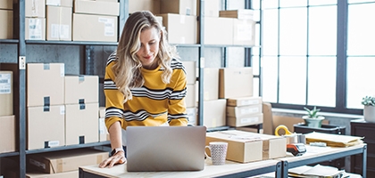 Female business owner on a laptop in a storage room.