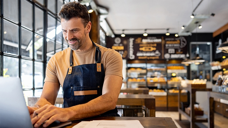 Business owner working on a laptop in his cafe.