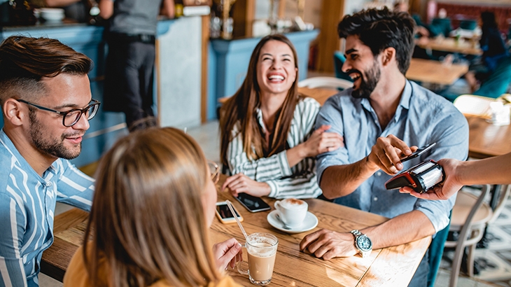 Four friends hanging out in a cafe and smiling