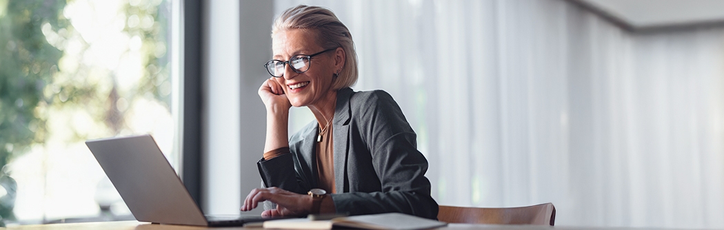 Business woman with laptop at desk in office.