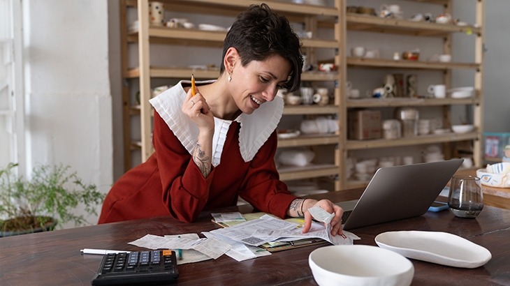 A businesswoman is doing bookkeeping in her ceramics shop.