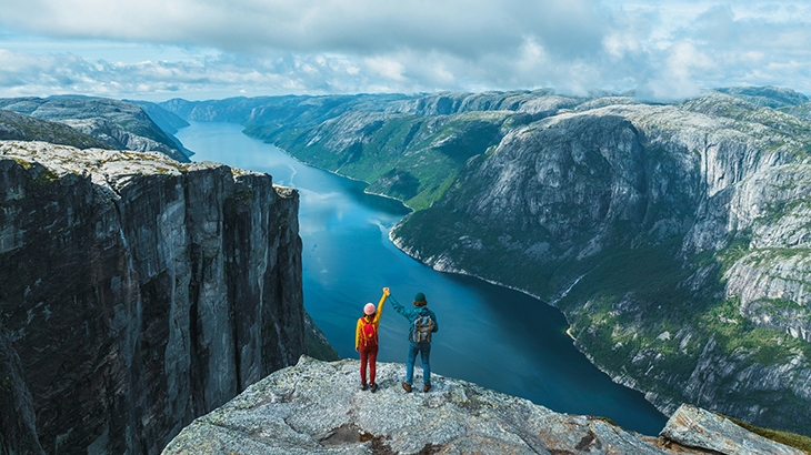 Man and woman raising arms in mountains in Norway.