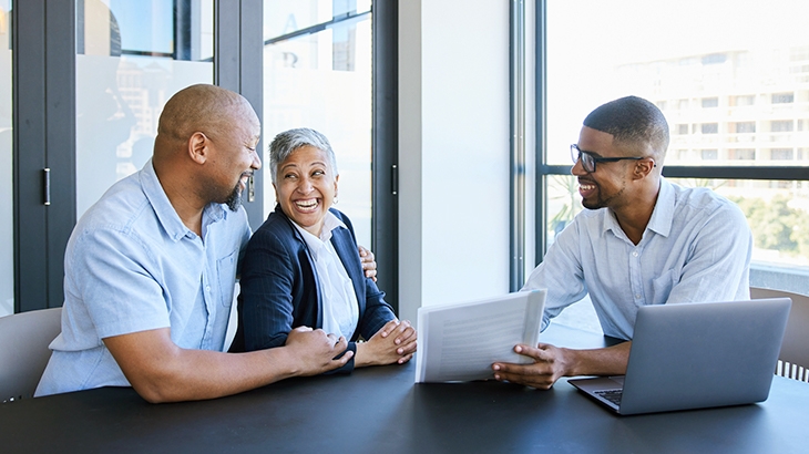 Mature couple smiling while going over savings account options with financial advisor.